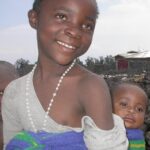 A girl carrying a baby boy
