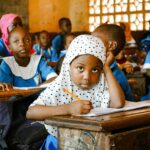 African children in a classroom, focused on learning activities.